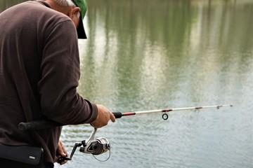 A seniorman holding a rod and reel fishing on the soft focus background of the pond and reflection, Spring in GA USA.