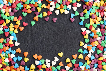 Colorful heart shaped sprinkles on black background