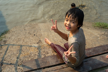 Portrait Asian wet girl enjoys plays the slider in the mud pond in the farm.