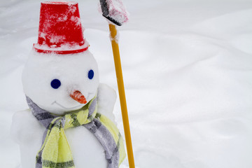 Snowman in red hat and scarf made by children. Closeup, selective focus