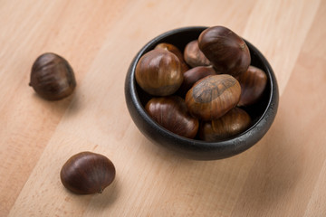 Maronen Esskastanien in schwarzer Schale auf Holz Hintergrund 