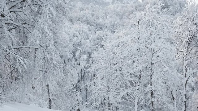 Aerial view over snowy mountain ridge valley with clouds, cable car lifting. Outdoor snow alpine wild nature tourist gondola transportation in winter. High altitude gondola in winter. Ski Gondola