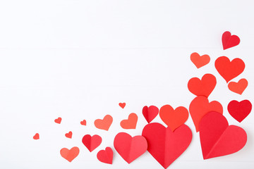 Red paper hearts on white wooden table