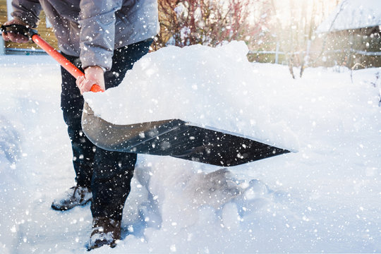 Man clearing snow by shovel after snowfall. Outdoors.