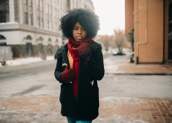 Young black woman is standing at city street.
