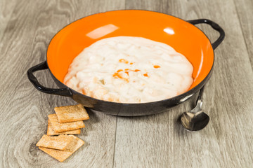Hot Sauce on New England Clam Chowder in Vintage Bowl on Rustic Wood Grain BG