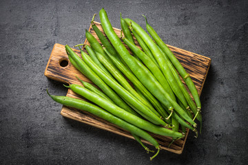 Green beans on black slate background.