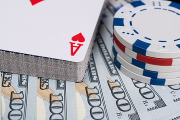 a deck of playing cards and poker chips lying on a fan of hundred dollar bills, background