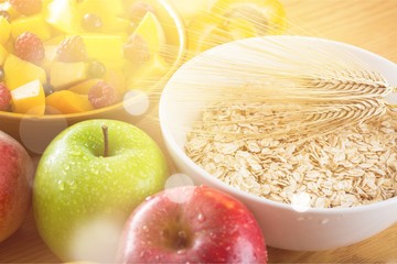 Raw oats in bowl and fruit salad, apples on the wooden table