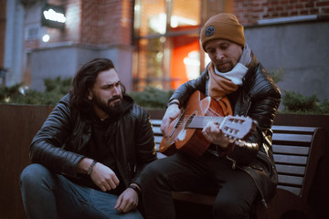 Obraz premium A company of friends on the bench plays the guitar.