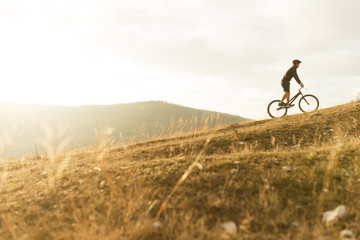 Anonymous sportsman on bicycle riding up hill