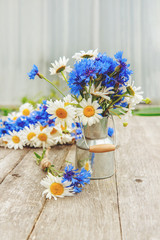 Making a bouquet of beautiful wild flowers of daisies and cornflowers on the background of the old wooden background. For congratulations. Copy space