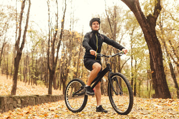 Fototapeta na wymiar Sportsman on bicycle in autumn park