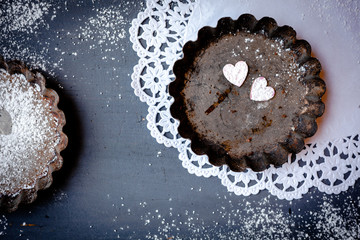 Liebe und Backen - Kleine Herzen aus Holz in Rosa in Backform auf blau grauen Holz