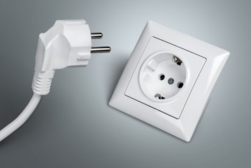 White electrical plug in the electric socket on a wall