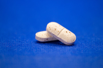 Many white medicine tablets on blue background. White pills, concept – pharmacy. Medicines drugs.
