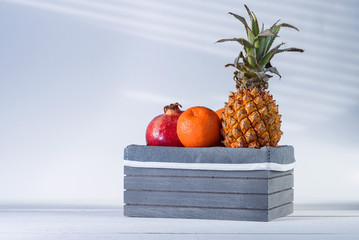 Fresh tropical fruits in grey wooden box.