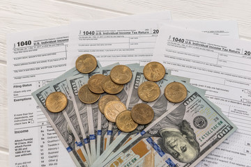 American dollars on 1040 tax form with wooden background