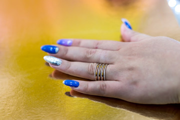Female hand with golden ring on golden background