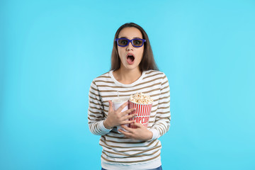 Fototapeta premium Emotional woman with 3D glasses, popcorn and beverage during cinema show on color background