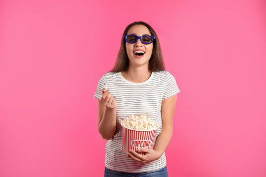 Woman with 3D glasses and popcorn during cinema show on color background
