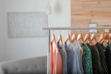 Wardrobe rack with stylish female clothes indoors, space for text