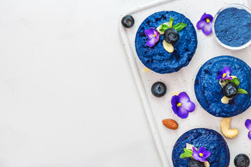 blueberry and butterfly pea flower vegan cashew cheesecakes with fresh berries, edible flowers, mint, nuts