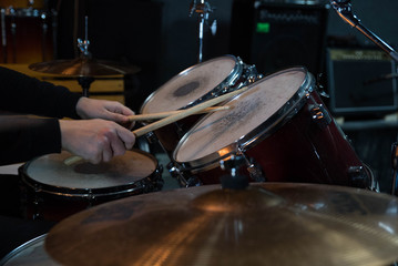 Professional drum set closeup. Drummer with drumsticks playing drums and cymbals, on the live music rock concert or in recording studio   