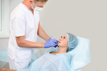 girl do plastic operation in medical clinic; doctor does lip augmentation surgery; injecting...