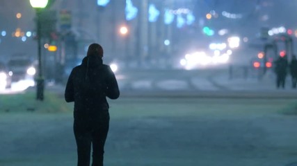 Runner silhouette running in winter city street during snowfall. Slow motion, 4K UHD.
