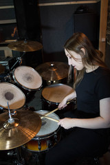 Fototapeta na wymiar Professional drum set closeup. Beautiful young girl drummer with drumsticks playing drums and cymbals, on the live music rock concert or in recording studio 