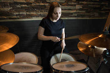 Professional drum set closeup. Beautiful young girl drummer with drumsticks playing drums and...