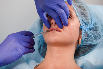 girl do plastic operation in medical clinic; doctor does lip augmentation surgery; injecting...