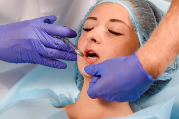 girl do plastic operation in medical clinic; doctor does lip augmentation surgery; injecting...