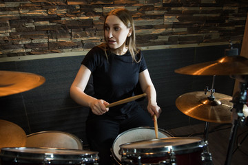 Fototapeta premium Professional drum set closeup. Beautiful young girl drummer with drumsticks playing drums and cymbals, on the live music rock concert or in recording studio 