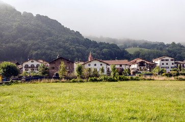 Fototapeta na wymiar House in the forest with fields in the mountains of the Pyrenees of Navarra in Spain in a cloudy day.