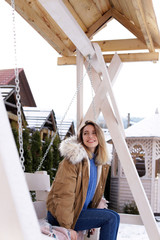 Young woman in warm clothes resting on outdoor swing. Winter vacation