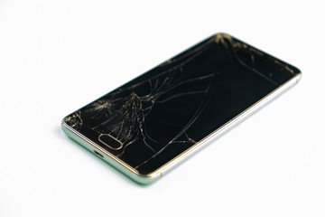 Mobile phone with broken black screen, top view. Distressed damaged smartphone in pale green background, shallow depth of field