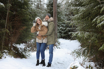 Obraz premium Couple in conifer forest on snowy day. Winter vacation