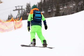 Snowboarder on slope at resort. Winter vacation