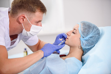 girl do plastic operation in medical clinic; doctor does lip augmentation surgery; injecting...