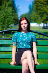 Girl are sitting on the green grass on the background of trees