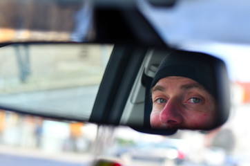 Mann sieht in den Rückspiegel in einem Auto