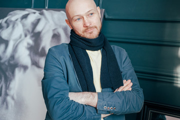 Portrait of attractive adult successful bald man art critic historian with beard in scarf in art...