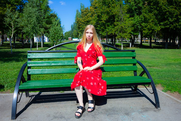 Girl are sitting on the green grass on the background of trees