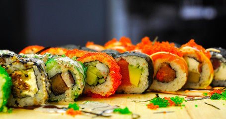 Eating Sushi with chopsticks. Sushi roll japanese food in restaurant. California Sushi roll set with salmon, vegetables, flying fish roe and caviar closeup. Japan restaurant menu