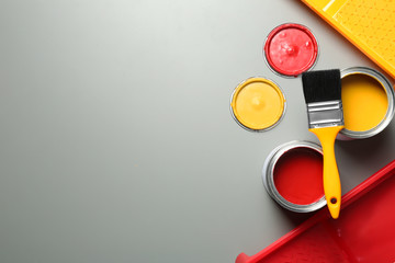 Flat lay composition with paint cans and brush on grey background. Space for text