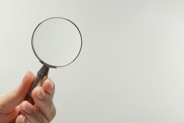 Woman holding magnifying glass on white background, closeup. Space for text