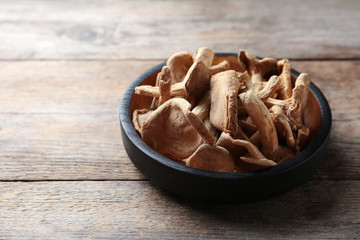 Plate of dried mushrooms on wooden background. Space for text
