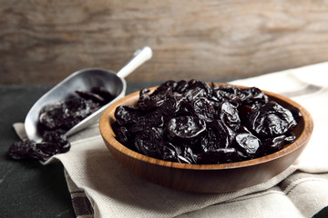 Plate and scoop of sweet dried plums on table. Healthy fruit